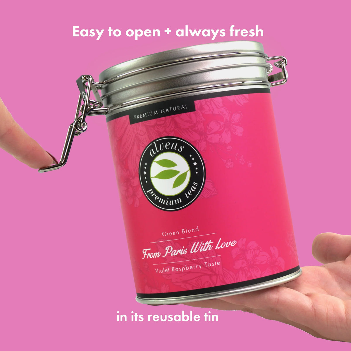 Hände öffnen den Bügelverschluss der pinkfarbenen From-Paris-with-Love-Teedose von alveus
