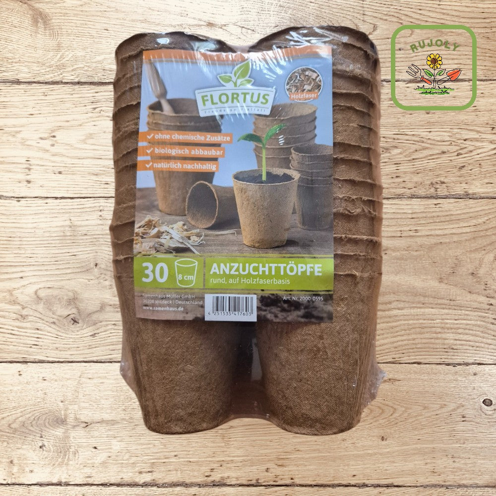 Biologisch abbaubarer Anzuchttopf aus Holzfaser direkt im Beet eingepflanzt – ideal für umweltfreundlichen Gartenbau