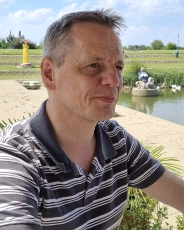 Mario Ruge, Gründer von RUJOLY, im gestreiften Poloshirt vor einem Teich in einer sonnigen Parkanlage